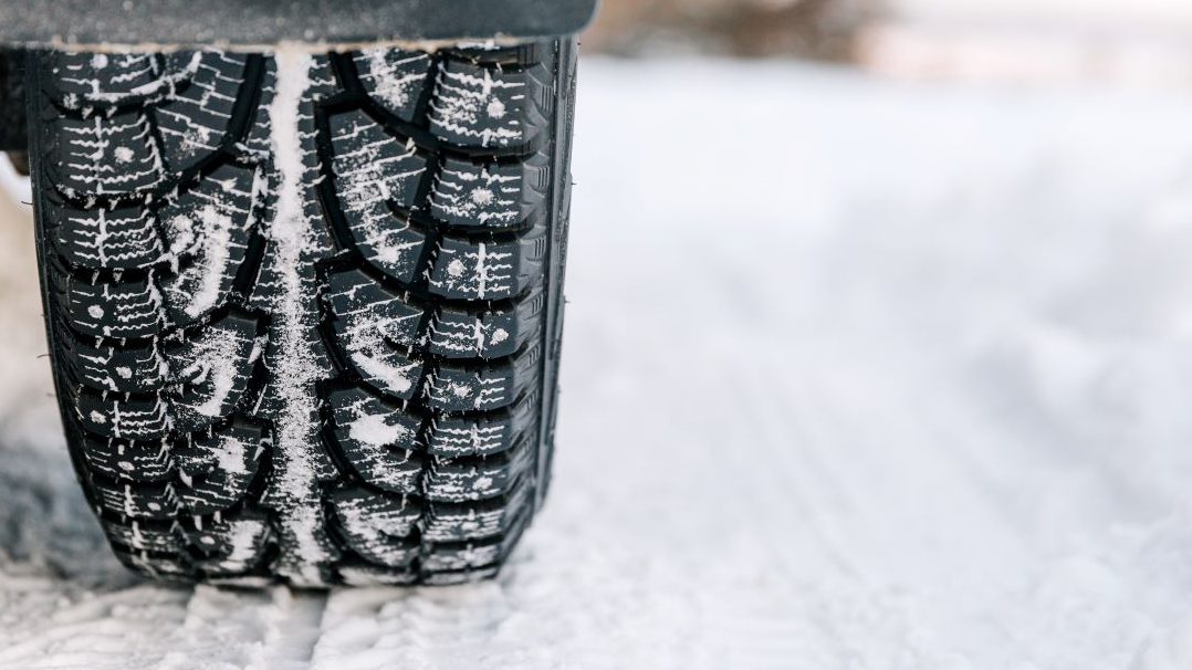 A close up of a tire in the snow at an automotive franchise.
