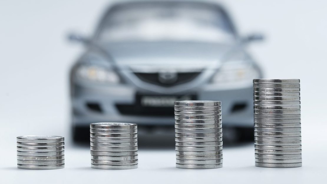 A stack of coins next to a silver automotive franchise.