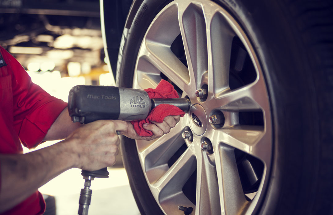 A mechanic is working on a tire at an automotive franchise.