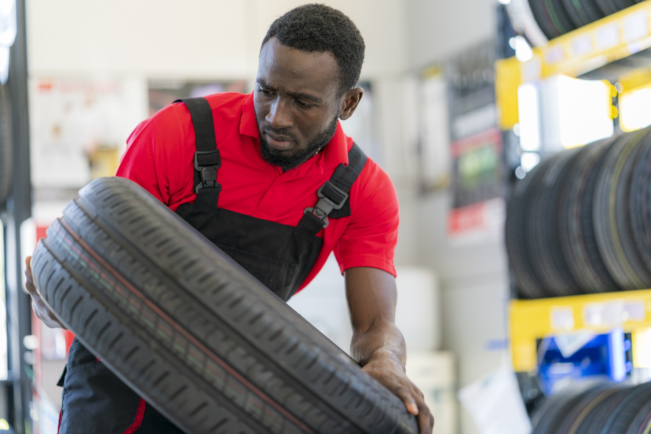 A man in an auto repair shop placing a tire on a shelf.