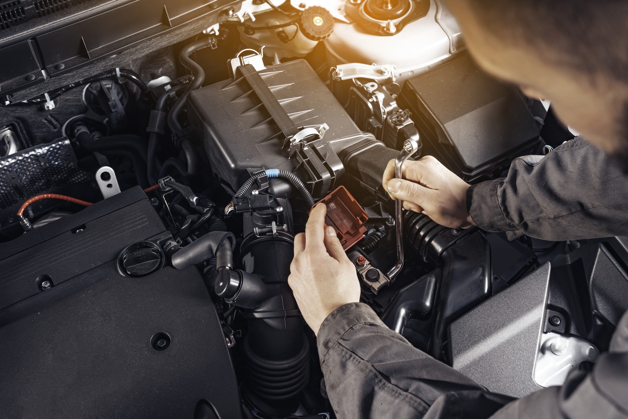 A mechanic working on the engine of an automotive franchise car.
