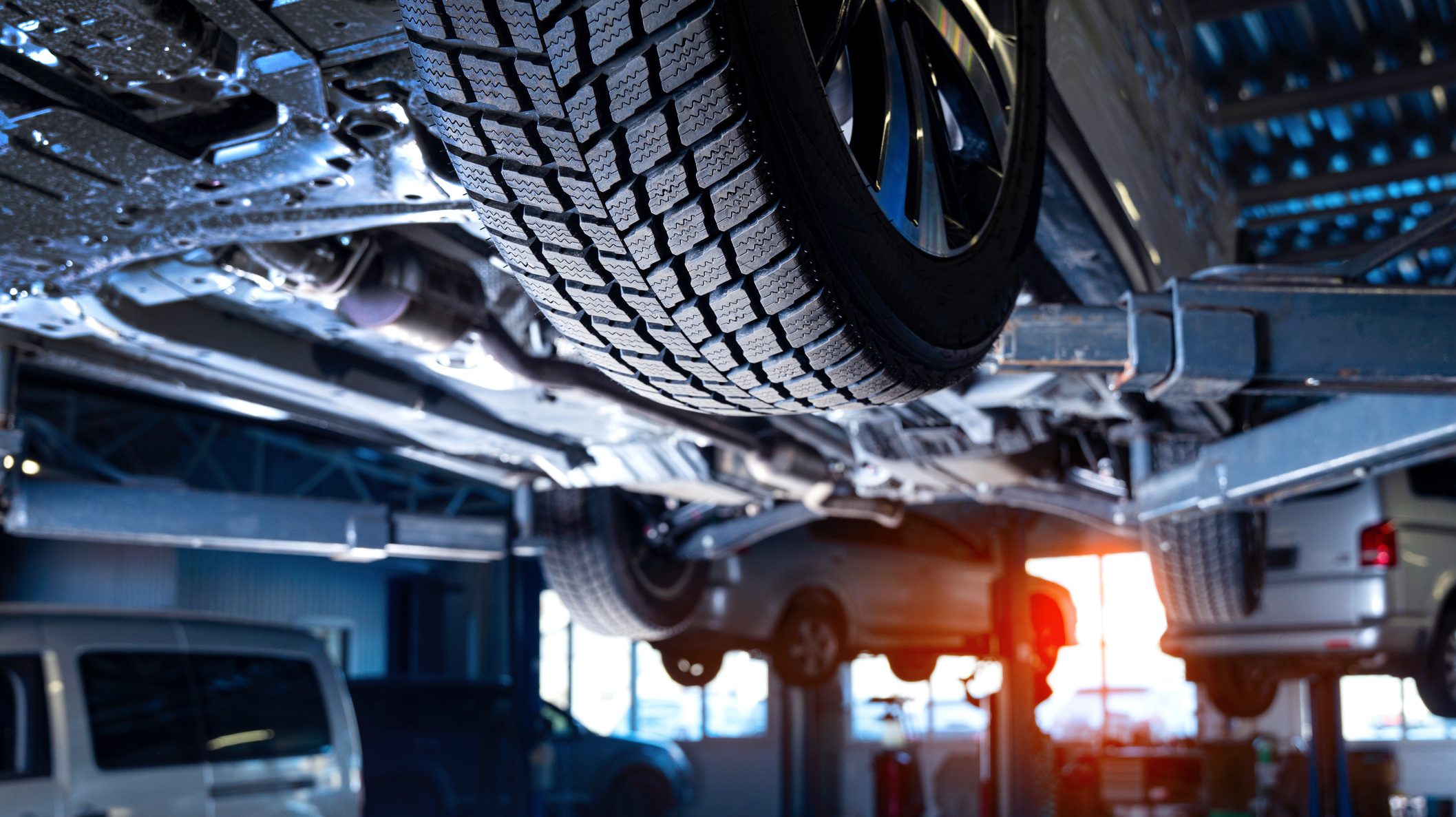 An automotive franchise car is on a lift in a garage.