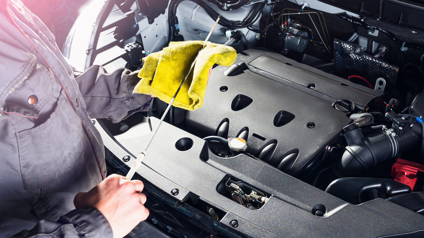 A mechanic is working on the engine of a car at an automotive franchise.
