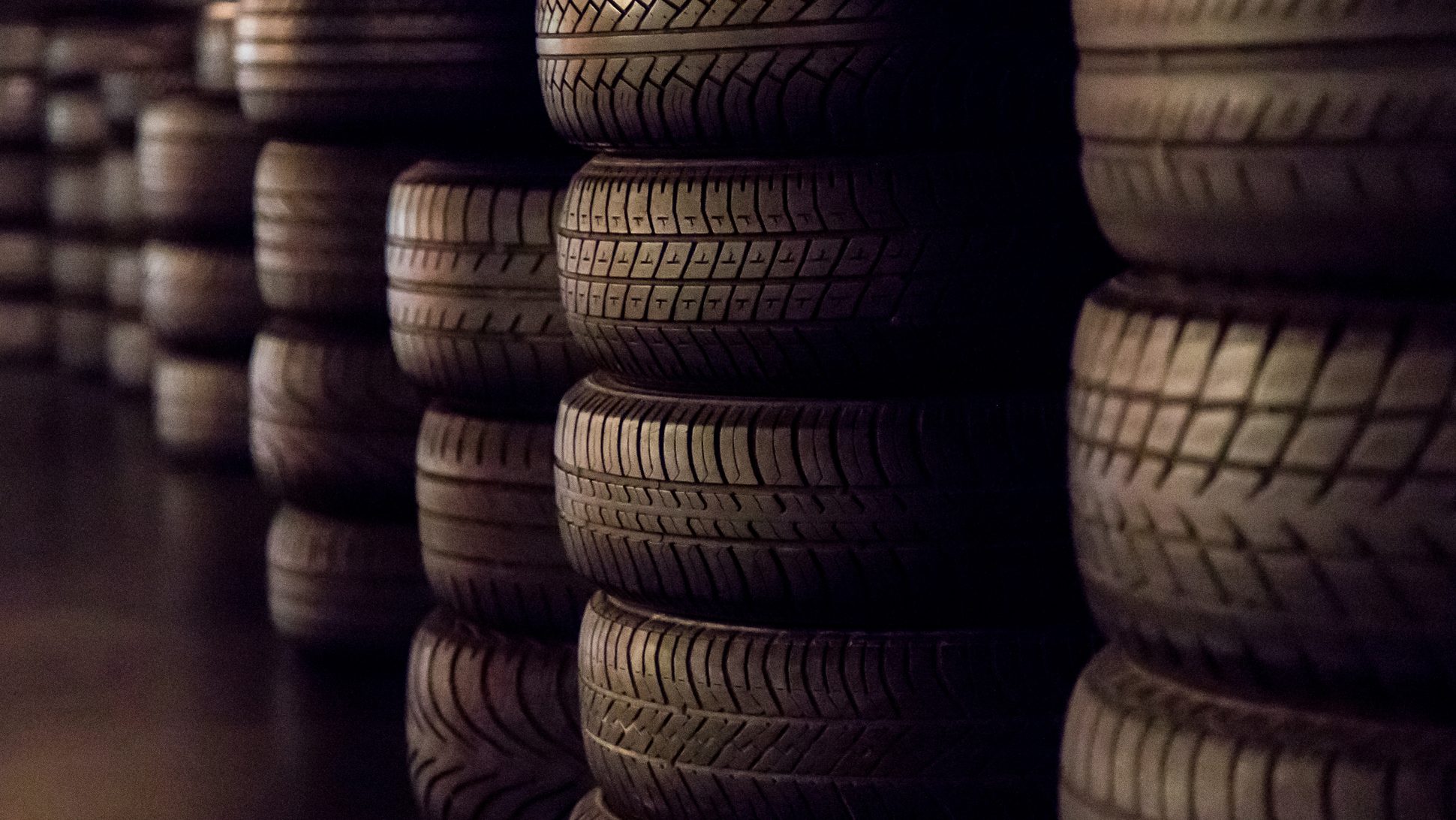 A row of tires in a dark room at an automotive franchise.