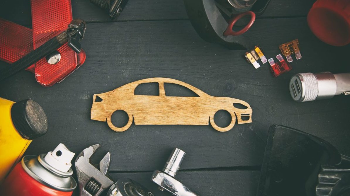 A wooden car and tools on a black background, showcasing a tire.