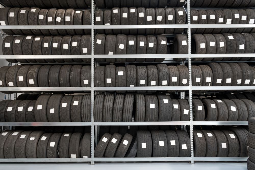 A lot of tires on a shelf in an automotive franchise garage.